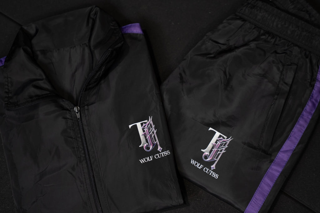 TJ Wolf Cutss black shell tracksuit jacket and bottoms laid flat with purple trim