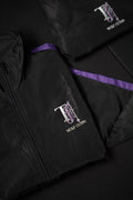 Black TJ Wolf Cutss tracksuit jacket and pants folded flat, showing purple side stripe and chest logo
