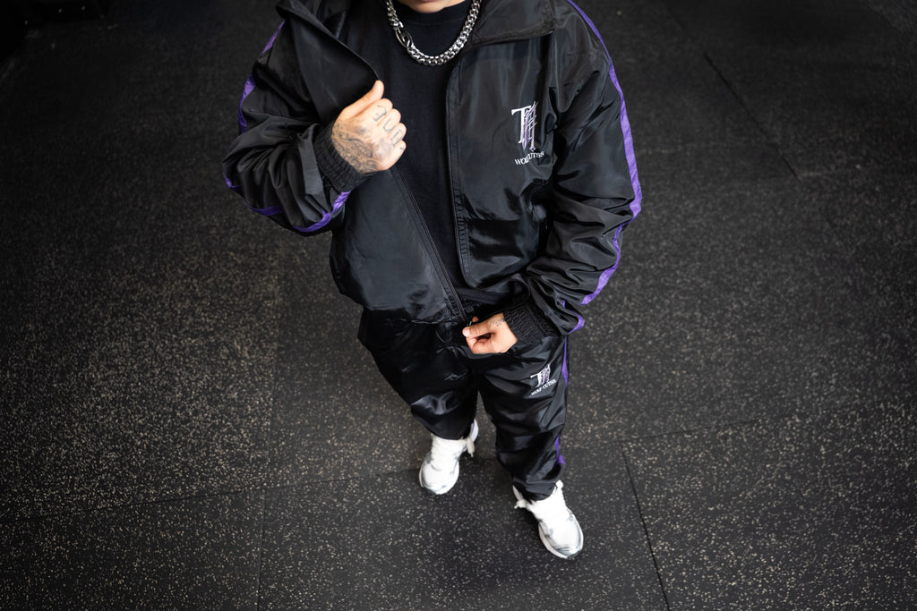 Overhead shot of a model wearing the full black TJ Wolf Cutss tracksuit with white trainers