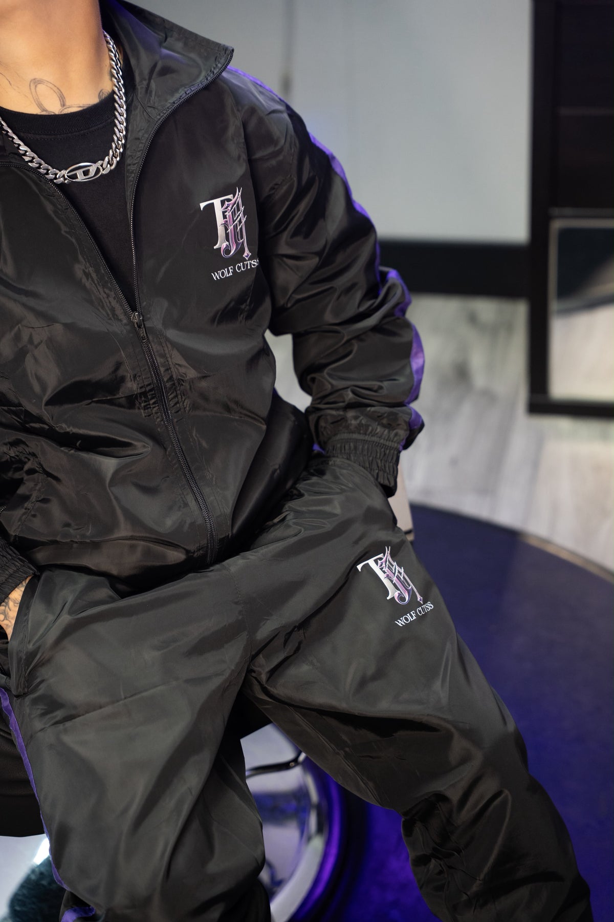 Model wearing the TJ Wolf Cutss tracksuit from behind at a gym pulldown machine, back logo visible