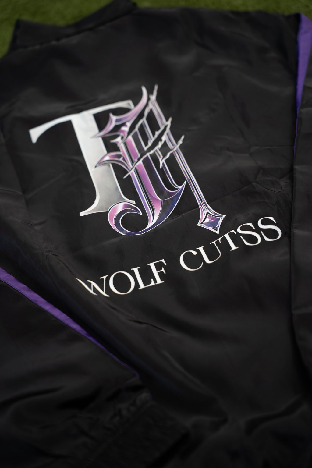 Close-up of the purple and silver TJ Wolf Cutss logo on the back of the tracksuit jacket