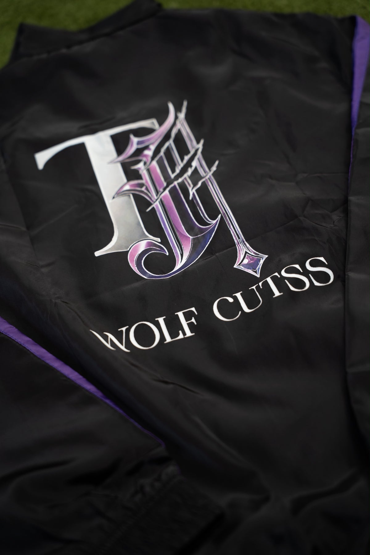 Close-up of the purple and silver TJ Wolf Cutss logo on the back of the tracksuit jacket